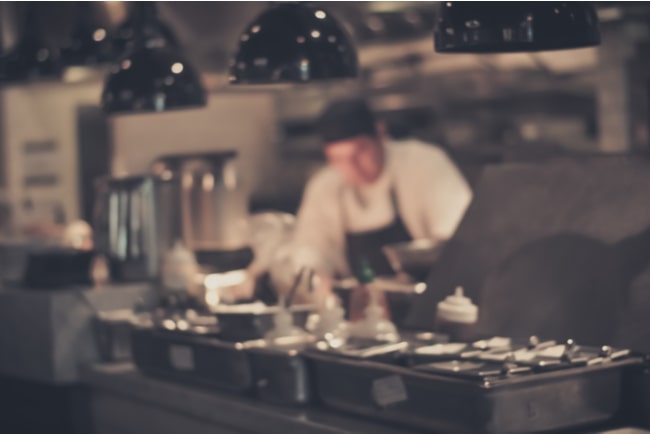 Blurrad bild på restaurangkök med en kock.